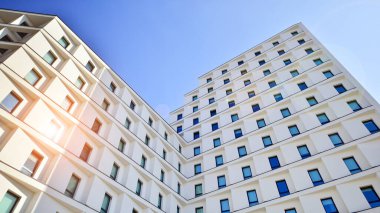 Beyaz, modern bir apartman manzarası. Mavi gökyüzü ile mükemmel bir simetri. Geometrik mimari modern beton yapı yapısını detaylandırıyor. Soyut somut mimari. 