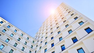 Beyaz, modern bir apartman manzarası. Mavi gökyüzü ile mükemmel bir simetri. Geometrik mimari modern beton yapı yapısını detaylandırıyor. Soyut somut mimari. 