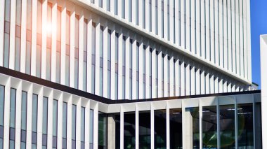 Şehrin modern ofis binası. Pencereleri, çeliği ve alüminyum panelleri var. Çağdaş ticari mimari, dikey geometrik çizgiler.