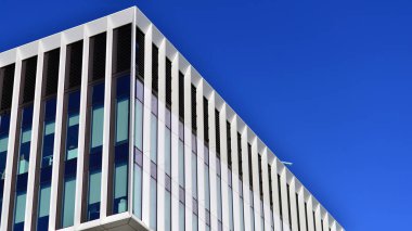 Şehrin modern ofis binası. Pencereleri, çeliği ve alüminyum panelleri var. Çağdaş ticari mimari, dikey geometrik çizgiler.