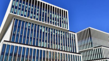 Şehrin modern ofis binası. Pencereleri, çeliği ve alüminyum panelleri var. Çağdaş ticari mimari, dikey geometrik çizgiler.