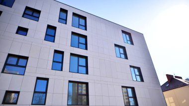 Beyaz, modern bir apartman manzarası. Mavi gökyüzü ile mükemmel bir simetri. Geometrik mimari modern beton yapı yapısını detaylandırıyor. Soyut somut mimari. 