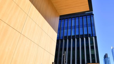 Cam cepheli modern ofis binası. Ofis binasının şeffaf cam duvarı. Binanın ön cephesinde mavi gökyüzünün yansıması.