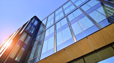Cam cepheli modern ofis binası. Ofis binasının şeffaf cam duvarı. Binanın ön cephesinde mavi gökyüzünün yansıması.