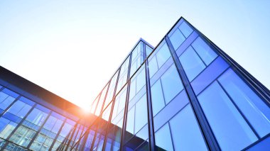 Cam cepheli modern ofis binası. Ofis binasının şeffaf cam duvarı. Binanın ön cephesinde mavi gökyüzünün yansıması.