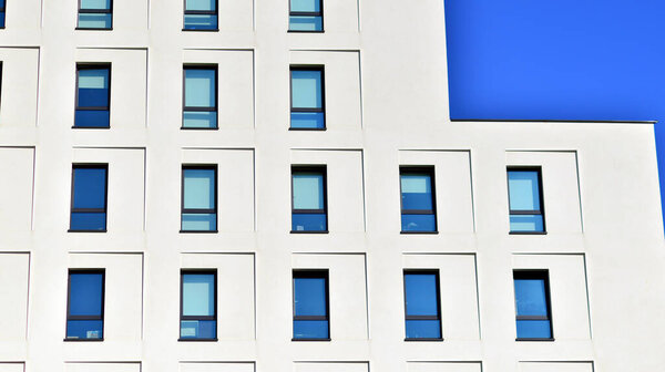 View of a white modern apartment building. Perfect symmetry with blue sky. Geometric architecture detail modern concrete structure building. Abstract concrete architecture.