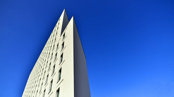 View of a white modern apartment building. Perfect symmetry with blue sky. Geometric architecture detail modern concrete structure building. Abstract concrete architecture.