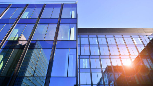 Modern office building with glass facade. Transparent glass wall of office building. Reflection of the blue sky on the facade of the building.