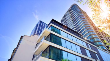 Çevre mimarisi. Yeşil ağaç ve yeni konut binası. Doğanın ve modernliğin ahengi. Yeşil yerleşim bölgesinde yeni daireleri olan modern bir apartman..