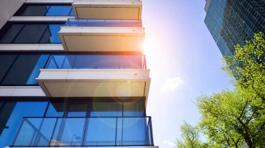 Çevre mimarisi. Yeşil ağaç ve yeni konut binası. Doğanın ve modernliğin ahengi. Yeşil yerleşim bölgesinde yeni daireleri olan modern bir apartman..