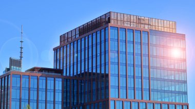 Binanın şeffaf yüzüyle cam bina ve mavi gökyüzü. Yapısal cam duvar mavi gökyüzünü yansıtıyor. 