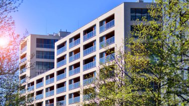 Çevre mimarisi. Yeşil ağaç ve yeni konut binası. Doğanın ve modernliğin ahengi. Yeşil yerleşim bölgesinde yeni daireleri olan modern bir apartman..