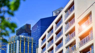 Çevre mimarisi. Yeşil ağaç ve yeni konut binası. Doğanın ve modernliğin ahengi. Yeşil yerleşim bölgesinde yeni daireleri olan modern bir apartman..