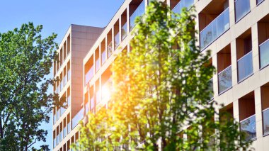 Çevre mimarisi. Yeşil ağaç ve yeni konut binası. Doğanın ve modernliğin ahengi. Yeşil yerleşim bölgesinde yeni daireleri olan modern bir apartman..