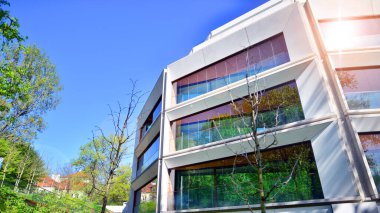 Çevre mimarisi. Yeşil ağaç ve yeni konut binası. Doğanın ve modernliğin ahengi. Yeşil yerleşim bölgesinde yeni daireleri olan modern bir apartman..