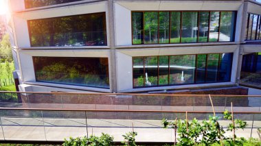 Çevre mimarisi. Yeşil ağaç ve yeni konut binası. Doğanın ve modernliğin ahengi. Yeşil yerleşim bölgesinde yeni daireleri olan modern bir apartman..