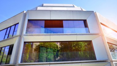 Çevre mimarisi. Yeşil ağaç ve yeni konut binası. Doğanın ve modernliğin ahengi. Yeşil yerleşim bölgesinde yeni daireleri olan modern bir apartman..