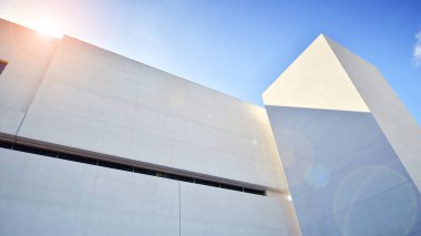 Beyaz Beton Binası 'nın yüzeyinde güneş ışığı ve gölge mavi gökyüzü arka planına karşı duvar, Minimal Sokak fotoğrafçılık tarzında Geometrik Dış Mimari