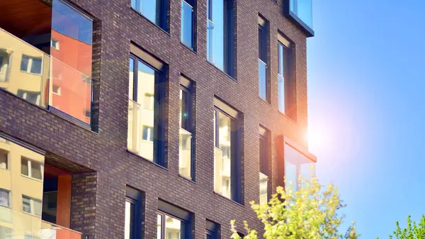 Çevre mimarisi. Yeşil ağaç ve yeni konut binası. Doğanın ve modernliğin ahengi. Yeşil yerleşim bölgesinde yeni daireleri olan modern bir apartman..