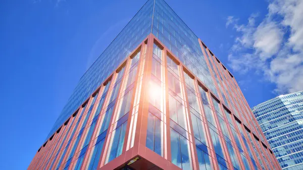 Glass building with transparent facade of the building and blue sky. Structural glass wall reflecting blue sky. Abstract modern architecture fragment. Contemporary architectural background.