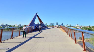 Varşova, Polonya. 11 Nisan 2024. Vistula Nehri üzerindeki köprü sadece yayalar ve bisikletçiler içindir. Arka planda, gökdelenleri olan bir şehir manzarası var..