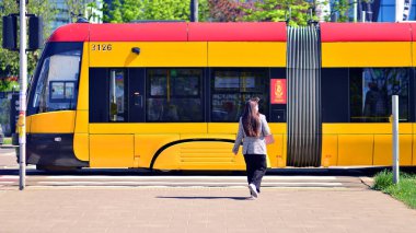 Varşova, Polonya. 11 Nisan 2024. Merkezde bir tren durağı var. Kadın şehir tramvayı bekliyor..
