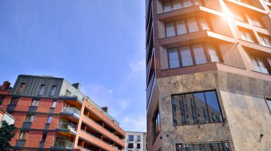 Gündüz gözüyle modern yerleşim yerinin dış tarafında. Mavi gökyüzü olan güneşli bir günde modern apartman binaları. Modern bir apartmanın cephesi