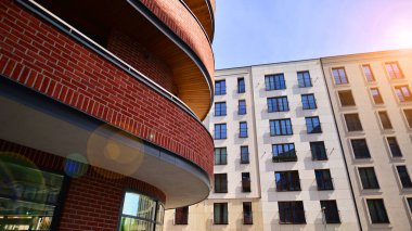 Gündüz gözüyle modern yerleşim yerinin dış tarafında. Mavi gökyüzü olan güneşli bir günde modern apartman binaları. Modern bir apartmanın cephesi