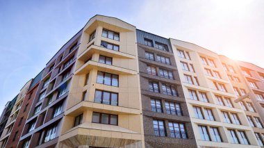 Gündüz gözüyle modern yerleşim yerinin dış tarafında. Mavi gökyüzü olan güneşli bir günde modern apartman binaları. Modern bir apartmanın cephesi