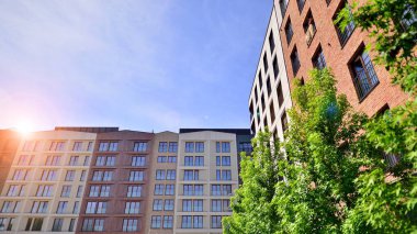 Yeşil yerleşim bölgesinde yeni daireleri olan modern bir yerleşim yeri. Çevre mimarisi. Yeşil ağaç ve yeni apartman. Doğanın ve modernliğin ahengi.