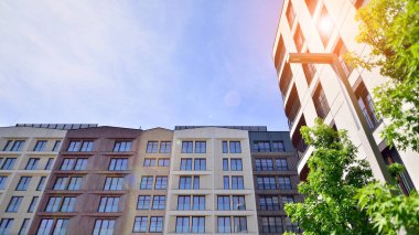 Yeşil yerleşim bölgesinde yeni daireleri olan modern bir yerleşim yeri. Çevre mimarisi. Yeşil ağaç ve yeni apartman. Doğanın ve modernliğin ahengi.