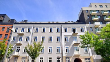 Yeşil yerleşim bölgesinde yeni daireleri olan modern bir yerleşim yeri. Çevre mimarisi. Yeşil ağaç ve yeni apartman. Doğanın ve modernliğin ahengi.