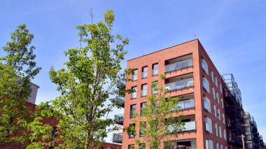 Yeşil yerleşim bölgesinde yeni daireleri olan modern bir yerleşim yeri. Çevre mimarisi. Yeşil ağaç ve yeni apartman. Doğanın ve modernliğin ahengi.