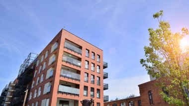 Yeşil yerleşim bölgesinde yeni daireleri olan modern bir yerleşim yeri. Çevre mimarisi. Yeşil ağaç ve yeni apartman. Doğanın ve modernliğin ahengi.