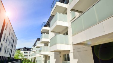 Gündüz gözüyle modern yerleşim yerinin dış tarafında. Mavi gökyüzü olan güneşli bir günde modern apartman binaları. Modern bir apartmanın cephesi