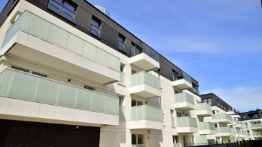 Gündüz gözüyle modern yerleşim yerinin dış tarafında. Mavi gökyüzü olan güneşli bir günde modern apartman binaları. Modern bir apartmanın cephesi
