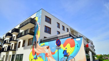 Gündüz gözüyle modern yerleşim yerinin dış tarafında. Mavi gökyüzü olan güneşli bir günde modern apartman binaları. Modern bir apartmanın cephesi