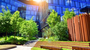 Karbondioksiti azaltmak için ağaçlı sürdürülebilir cam ofis binası. Modern şehirde çevre dostu bir bina. Yeşil çevresi olan bir ofis. Şirket binası CO2 'yi düşürdü.