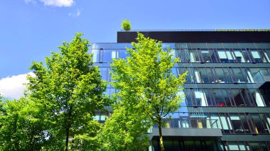 Karbondioksiti azaltmak için ağaçlı sürdürülebilir cam ofis binası. Modern şehirde çevre dostu bir bina. Yeşil çevresi olan bir ofis. Şirket binası CO2 'yi düşürdü.