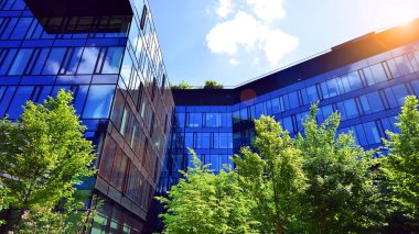 Karbondioksiti azaltmak için ağaçlı sürdürülebilir cam ofis binası. Modern şehirde çevre dostu bir bina. Yeşil çevresi olan bir ofis. Şirket binası CO2 'yi düşürdü.