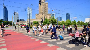 Varşova, Polonya. 8 Haziran 2024. Büyük bir şehrin caddesi. Farklı yaşlarda insanlar karşıdan karşıya geçiyor. Şehir caddesi manzarası sakinleri, turistler ve modern binalar. Şehir merkezinde güneşli bir günde.