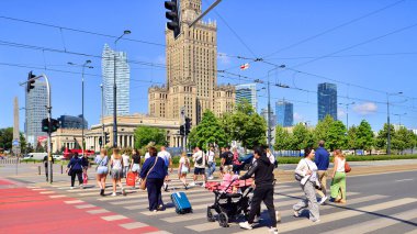 Varşova, Polonya. 8 Haziran 2024. Büyük bir şehrin caddesi. Farklı yaşlarda insanlar karşıdan karşıya geçiyor. Şehir caddesi manzarası sakinleri, turistler ve modern binalar. Şehir merkezinde güneşli bir günde.