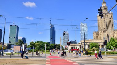 Varşova, Polonya. 8 Haziran 2024. Büyük bir şehrin caddesi. Farklı yaşlarda insanlar karşıdan karşıya geçiyor. Şehir caddesi manzarası sakinleri, turistler ve modern binalar. Şehir merkezinde güneşli bir günde.
