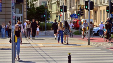 Varşova, Polonya. 8 Haziran 2024. Büyük bir şehrin caddesi. Farklı yaşlarda insanlar karşıdan karşıya geçiyor. Şehir caddesi manzarası sakinleri, turistler ve modern binalar. Şehir merkezinde güneşli bir günde.