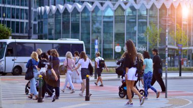 Varşova, Polonya. 8 Haziran 2024. Büyük bir şehrin caddesi. Farklı yaşlarda insanlar karşıdan karşıya geçiyor. Şehir caddesi manzarası sakinleri, turistler ve modern binalar. Şehir merkezinde güneşli bir günde.