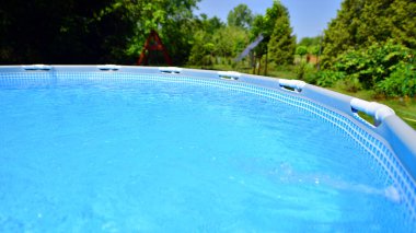 Ev ve bahçe için metal çerçeveli yüzme havuzu. Bahçedeki yüzme havuzunu çerçevele. Arka planda bahçe var. Yaz tatili eğlencesi ve eğlence.