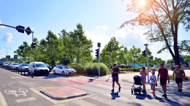 Varşova, Polonya. 9 Temmuz 2024. Şehir merkezinde güneşli bir günde ve büyük bir şehrin caddesinde. Farklı yaşlarda insanlar karşıdan karşıya geçiyor. Şehir caddesi manzarası sakinleri, turistler ve modern binalar. 