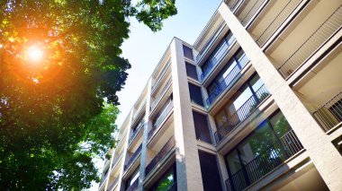 Yeşil yerleşim bölgesinde yeni daireleri olan modern bir yerleşim yeri. Çevre mimarisi. Yeşil ağaç ve yeni apartman. Doğanın ve modernliğin ahengi.