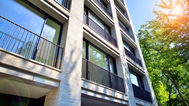 Yeşil yerleşim bölgesinde yeni daireleri olan modern bir yerleşim yeri. Çevre mimarisi. Yeşil ağaç ve yeni apartman. Doğanın ve modernliğin ahengi.