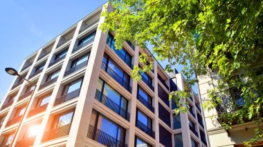 Yeşil yerleşim bölgesinde yeni daireleri olan modern bir yerleşim yeri. Çevre mimarisi. Yeşil ağaç ve yeni apartman. Doğanın ve modernliğin ahengi.